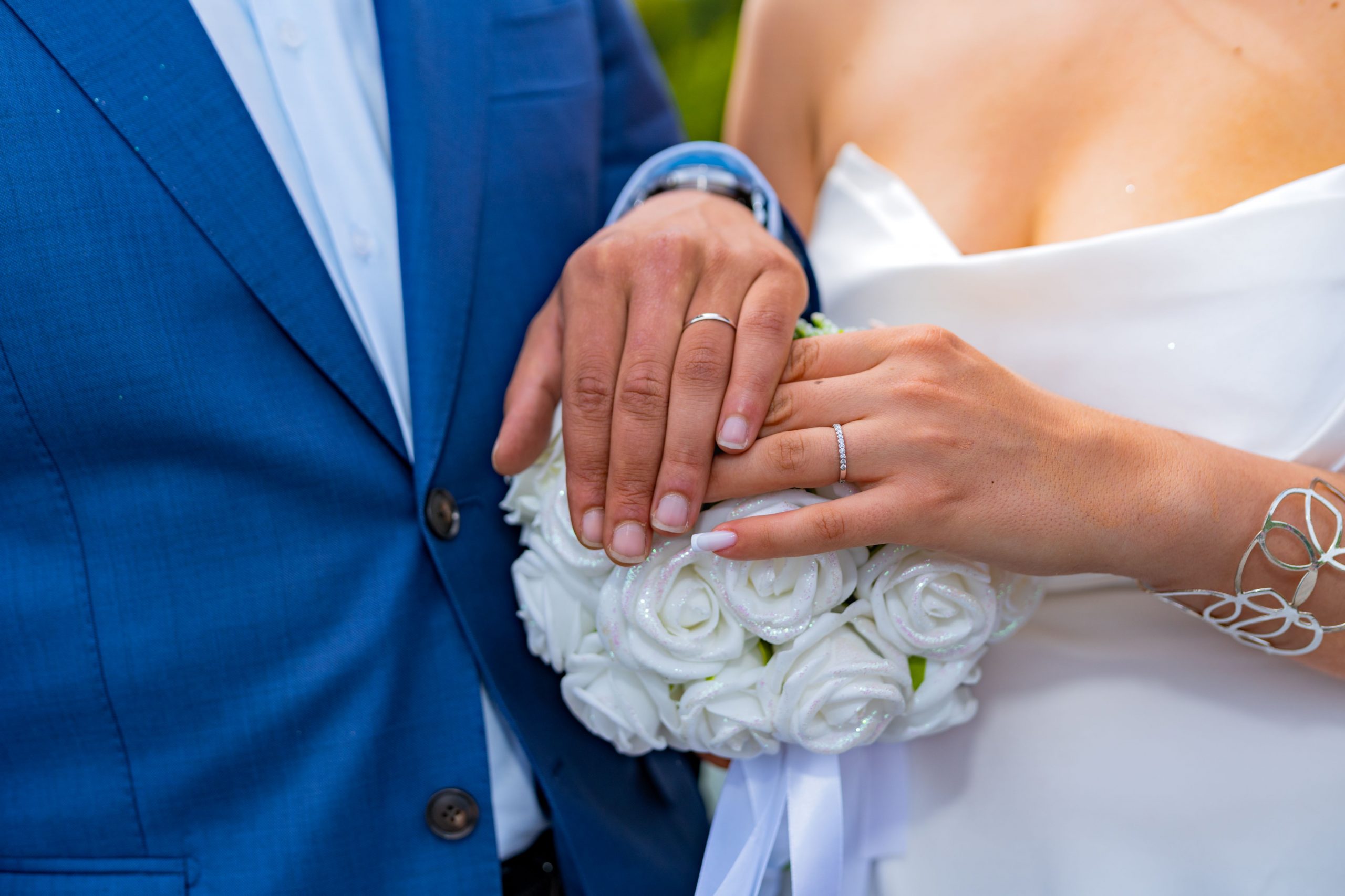 Close-up of bride and groom's hands with wedding rings, symbolizing love and commitment.